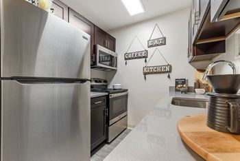 A kitchen with a refrigerator, oven, and microwave.